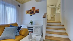 Un salon avec un canapé, une console blanche, un tableau et un escalier.