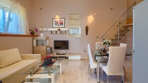 Un salon moderne comprenant un canapé, une table basse, un téléviseur et un coin repas avec des chaises.