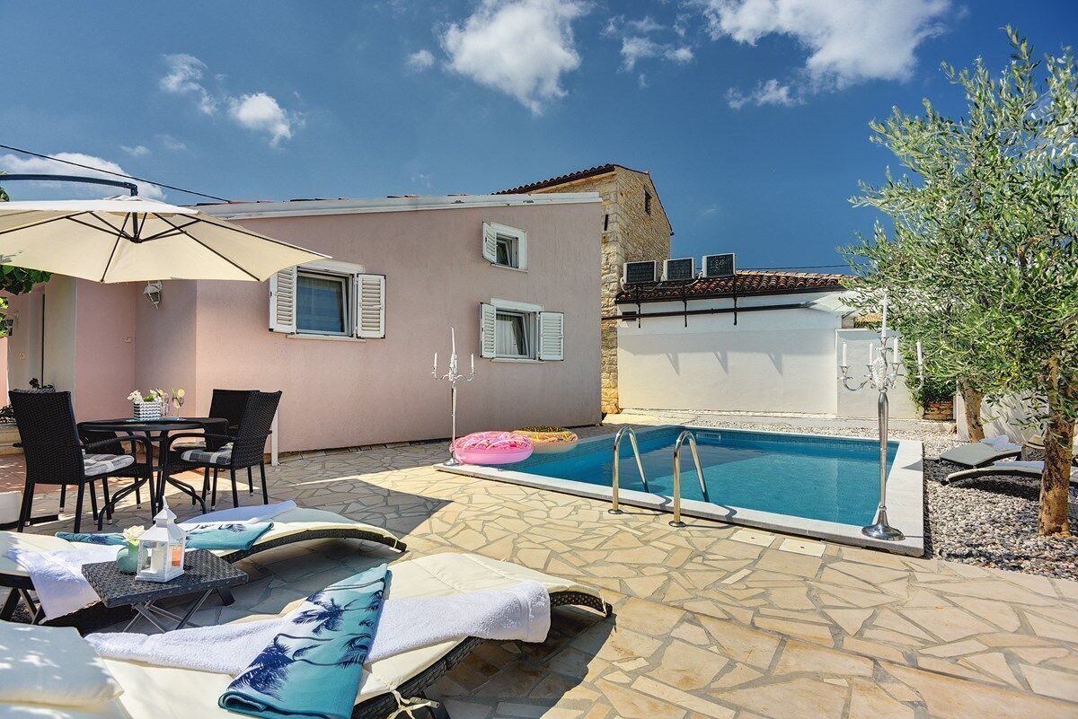 A poolside area with lounge chairs, a table, and an umbrella.
