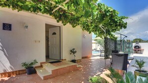 L’entrée d’un hôtel, avec un patio couvert, des marches menant à la porte et des plantes en pot.