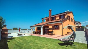 Une maison à deux étages avec un patio, une piscine et un fauteuil de relaxation.