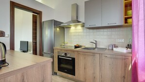 Une cuisine moderne avec des meubles en bois, un réfrigérateur en acier inoxydable, un four encastré et une grande fenêtre.