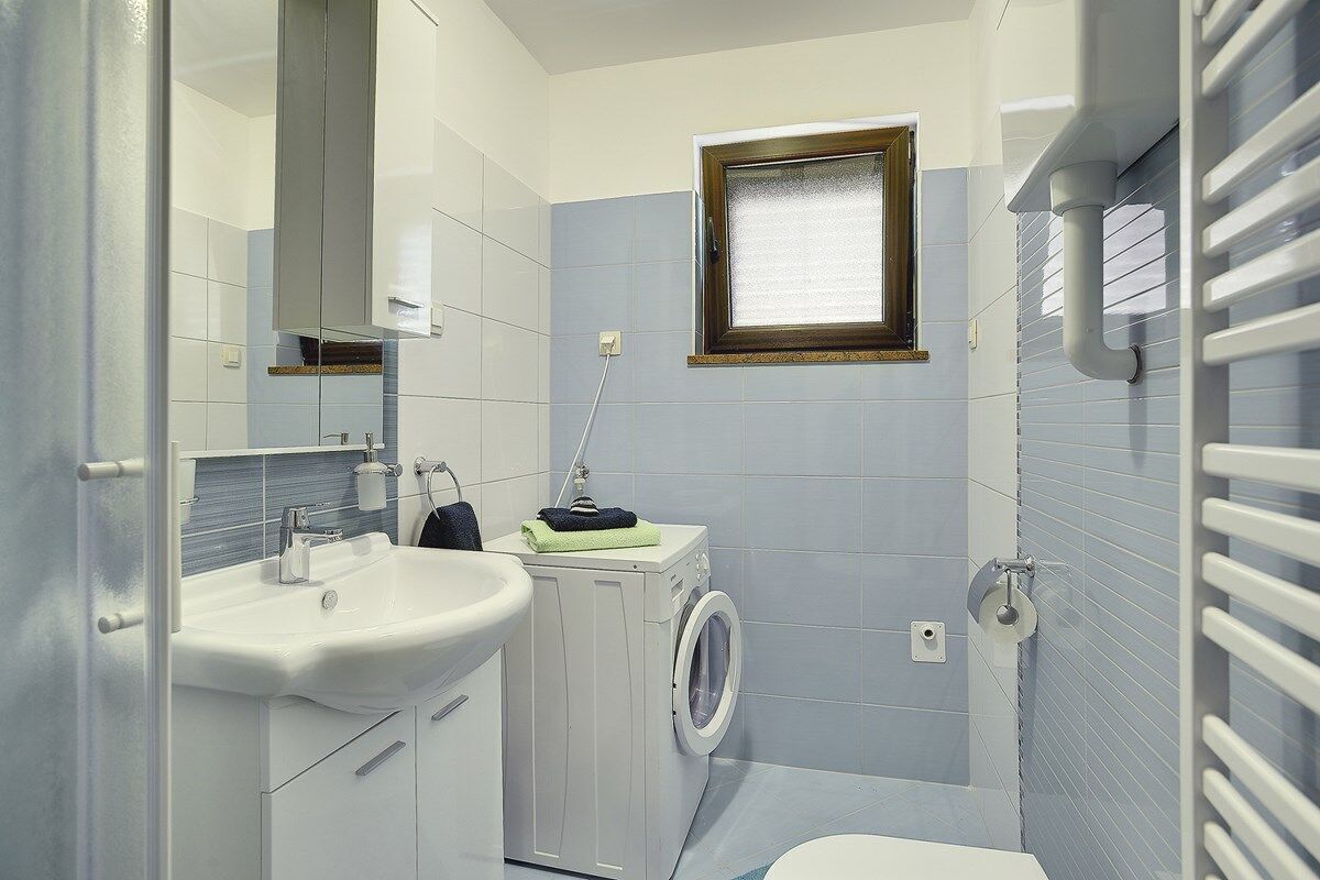 Pieni kylpyhuone, jossa on pesuallas, pesukone ja wc.