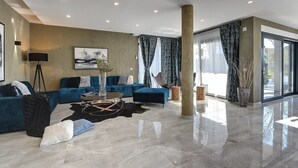 A spacious living area with a blue sofa set, a coffee table, and a large window with curtains. - Villa Orion - Private Heated Pool, Sauna & Jacuzzi (74027-K1) - Rovinj (Rovinj)
