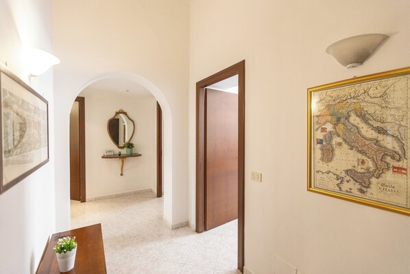 A hallway with a map, a mirror, and a small table with a plant. - Rental in Rome Pietroburgo Apartment (Rome)