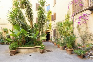 A narrow courtyard with potted plants and a central archway. - Rental in Rome Pietroburgo Apartment (Rome)