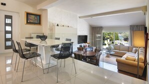 Un soggiorno moderno con zona pranzo, divano e televisione.