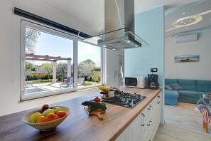 Eine moderne Küche mit einem großen Fenster, einer Holzausziehtheke und einem Essbereich mit einem blauen Sofa.