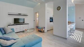 A modern living room with a sofa, TV, and a small coffee table. There is a kitchen visible in the background. - Villa Sunny Home (74045-K1) - Vodnjan (Vodnjan)