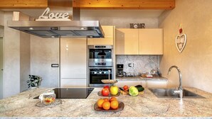 Uma cozinha moderna com bancada de mármore, eletrodomésticos de aço inoxidável e vigas de madeira no teto.
