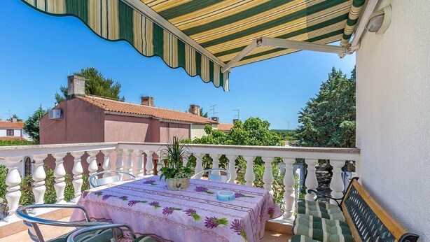 Ein Balkon mit Tisch für zwei Personen, Stühlen und einer Bank.