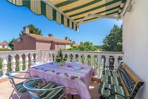 Ein Balkon mit Tisch für zwei Personen, Stühlen und einer Bank.