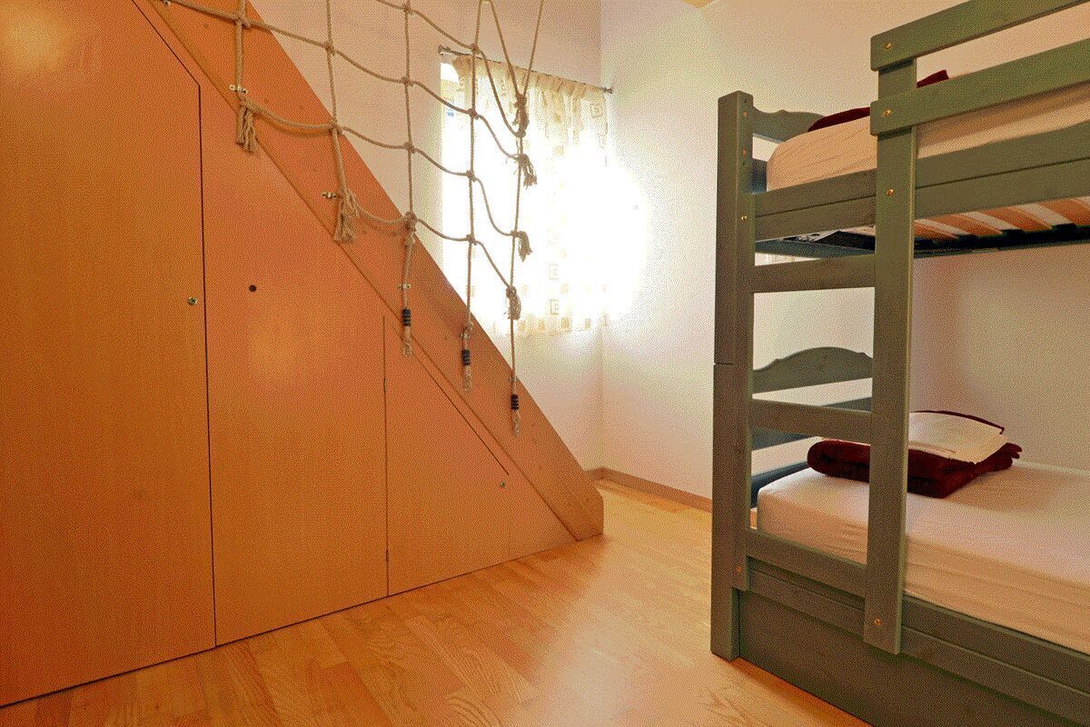 A bunk bed with a wooden ladder and a small shelf.