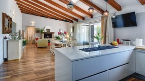 Cozinha moderna com ilha central, vigas de madeira no teto e área de jantar com mesa e cadeiras.
