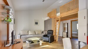 Ett modernt vardagsrum med en soffa, ett skrivbord, en stol, en våningssäng och en stege.