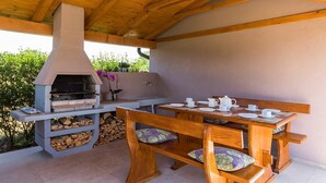 An outdoor patio with a wood-burning stove, a dining table with chairs, and a bench. - Villa Roma (74193-K1) - Pula (Pula)