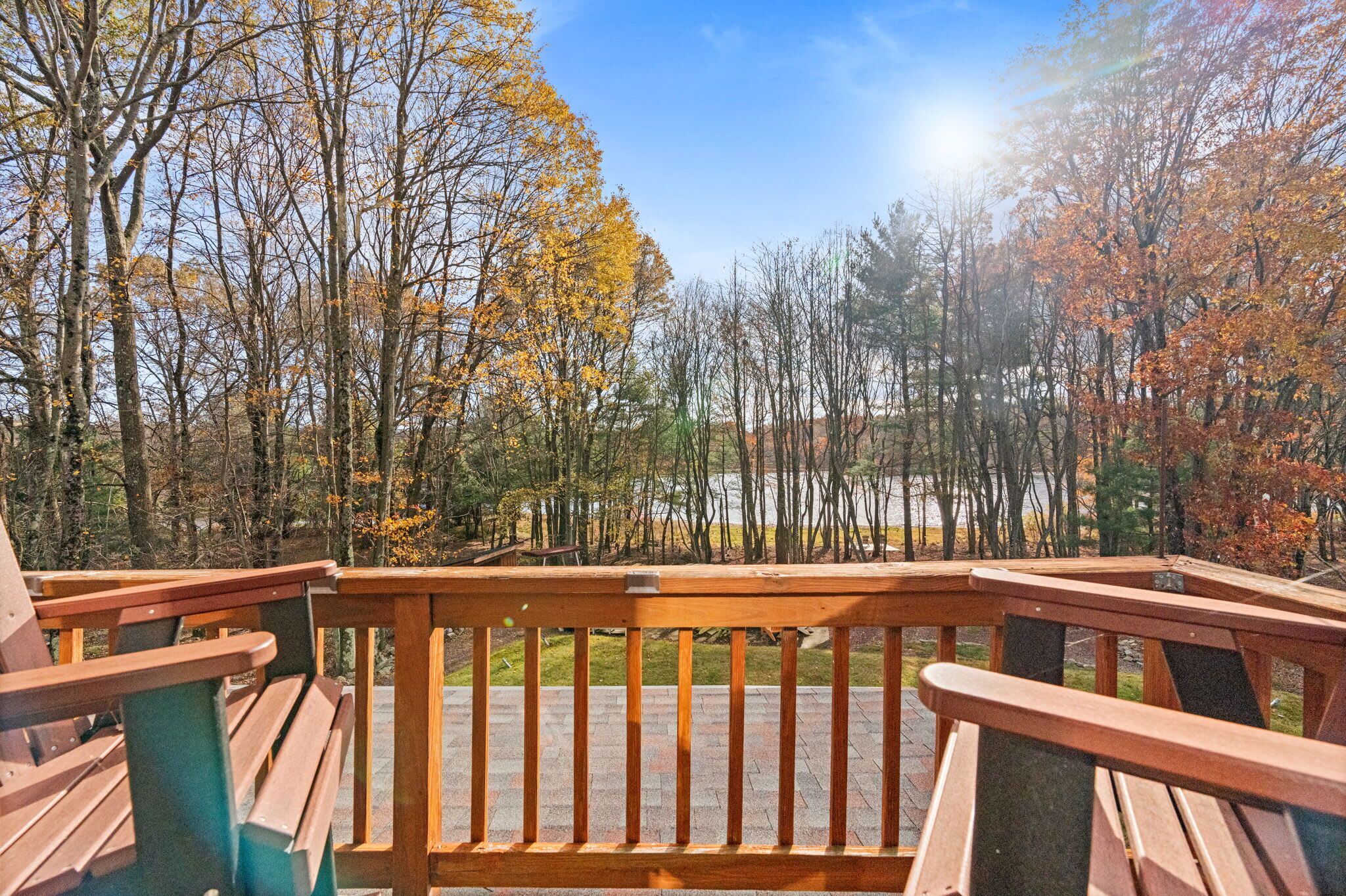 Une terrasse en bois, dotée de bancs, qui offre une vue sur une zone boisée aux couleurs automnales.