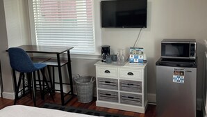 A hotel room with a bed, a desk with a chair, a television, a microwave, and a small refrigerator.