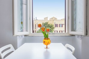 Une table blanche ornée d’un vase de tulipes, et une fenêtre donnant sur des immeubles.