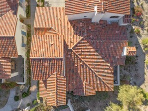 An aerial view of a residential area with terracotta-tiled roofs, a paved driveway, and a small garden with flowering plants. - Family Friendly Legacy Villas Retreat- Mountain Views (La Quinta)