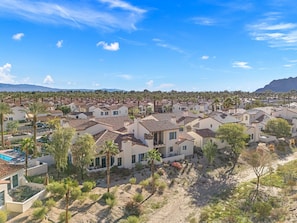 Zona residencial con casas de techo rojo, rodeada de vegetación y palmeras.