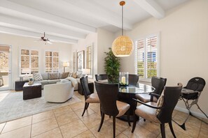 A spacious living area with a dining table, comfortable seating, and large windows. - Family Friendly Legacy Villas Retreat- Mountain Views (La Quinta)