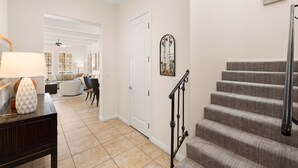 A staircase with a handrail, a door, and a wall-mounted mirror. - Family Friendly Legacy Villas Retreat- Mountain Views (La Quinta)