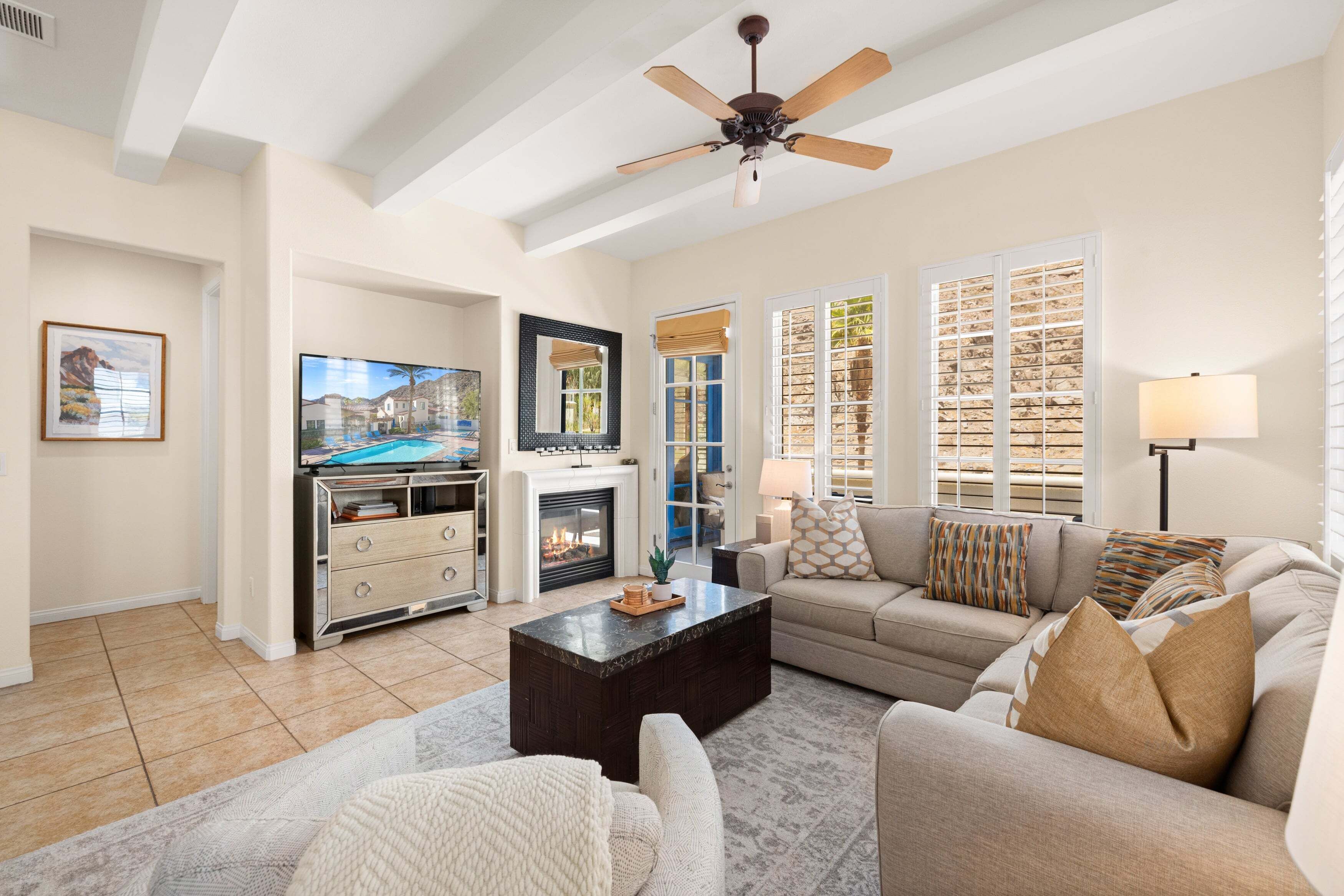Un salon avec une cheminée, un téléviseur et un ventilateur de plafond.