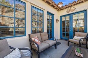 Eine Terrassenfläche mit einer Couch, Stühlen und einem kleinen Tisch.