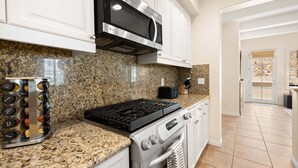 A kitchen with granite countertops, stainless steel appliances, and white cabinetry. - Family Friendly Legacy Villas Retreat- Mountain Views (La Quinta)