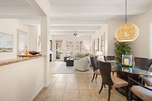 A spacious living area with a dining table, chairs, and a kitchen area with a counter.