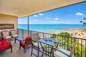 A balcony with outdoor furniture, a Chevrolet sign, and a view of the beach and ocean. - Oceanfront Hale Hui Kai 313 Large Lanai, AC, Incredible Views on Keawakapu Beach (Kihei)