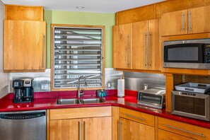 A kitchen with wooden cabinets, a stainless steel microwave, a toaster, and a dishwasher. - Oceanfront Hale Hui Kai 313 Large Lanai, AC, Incredible Views on Keawakapu Beach (Kihei)
