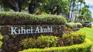 A stone wall with the name "Kihei Akahi" and lush greenery around it. - Budget Friendly - Kihei Akahi C-608, Ocean Views, Short Walk to Kamaole Beach II (Kihei)