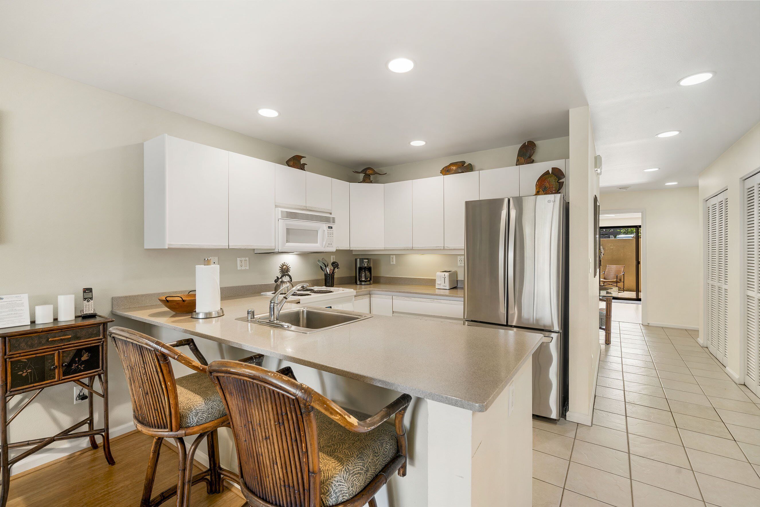 A modern kitchen with white cabinets, stainless steel appliances, and a large island with bar stools.