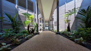 A covered walkway with a gravel path flanked by plants and columns. - Hale Hui Kai 106 - Beautiful Ground Floor Unit, on Keawakapu Beach, Split AC! (Kihei)