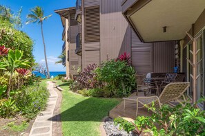 Um edifício residencial com pátio, mobiliário exterior e vista para o oceano.