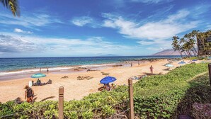 A beach with umbrellas, a clear sky, and a mountain in the distance. - Hale Hui Kai 106 - Beautiful Ground Floor Unit, on Keawakapu Beach, Split AC! (Kihei)