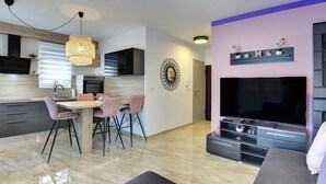 Een moderne keuken met een eethoek, een grote flatscreen-tv en een gezellige zithoek.