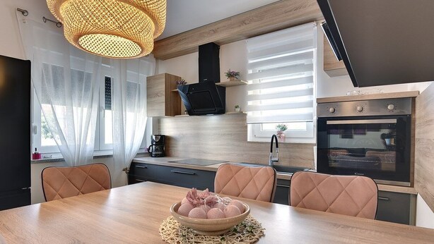 Een moderne keuken met een eettafel, stoelen en een schaal met eten.