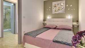 Een slaapkamer met een bed, nachtkastjes, een kunstwerk aan de muur en een douche.