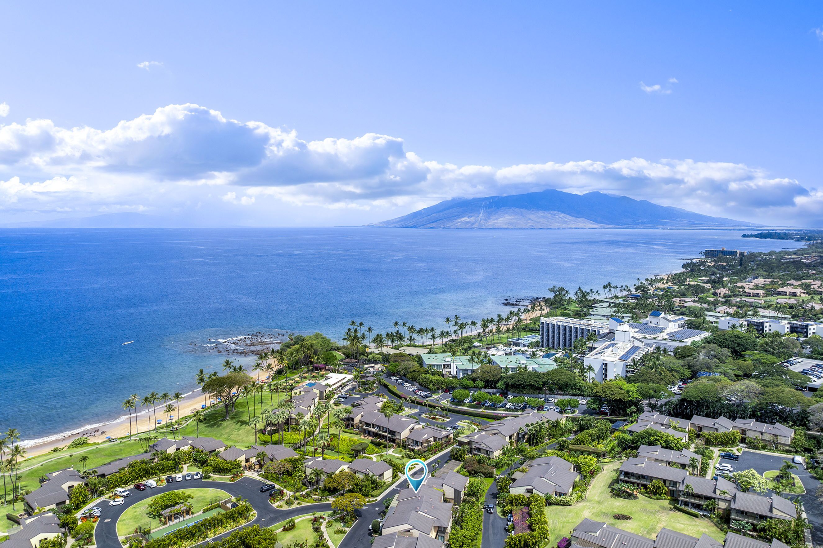 A coastal residential area with houses, a road, and a beach.