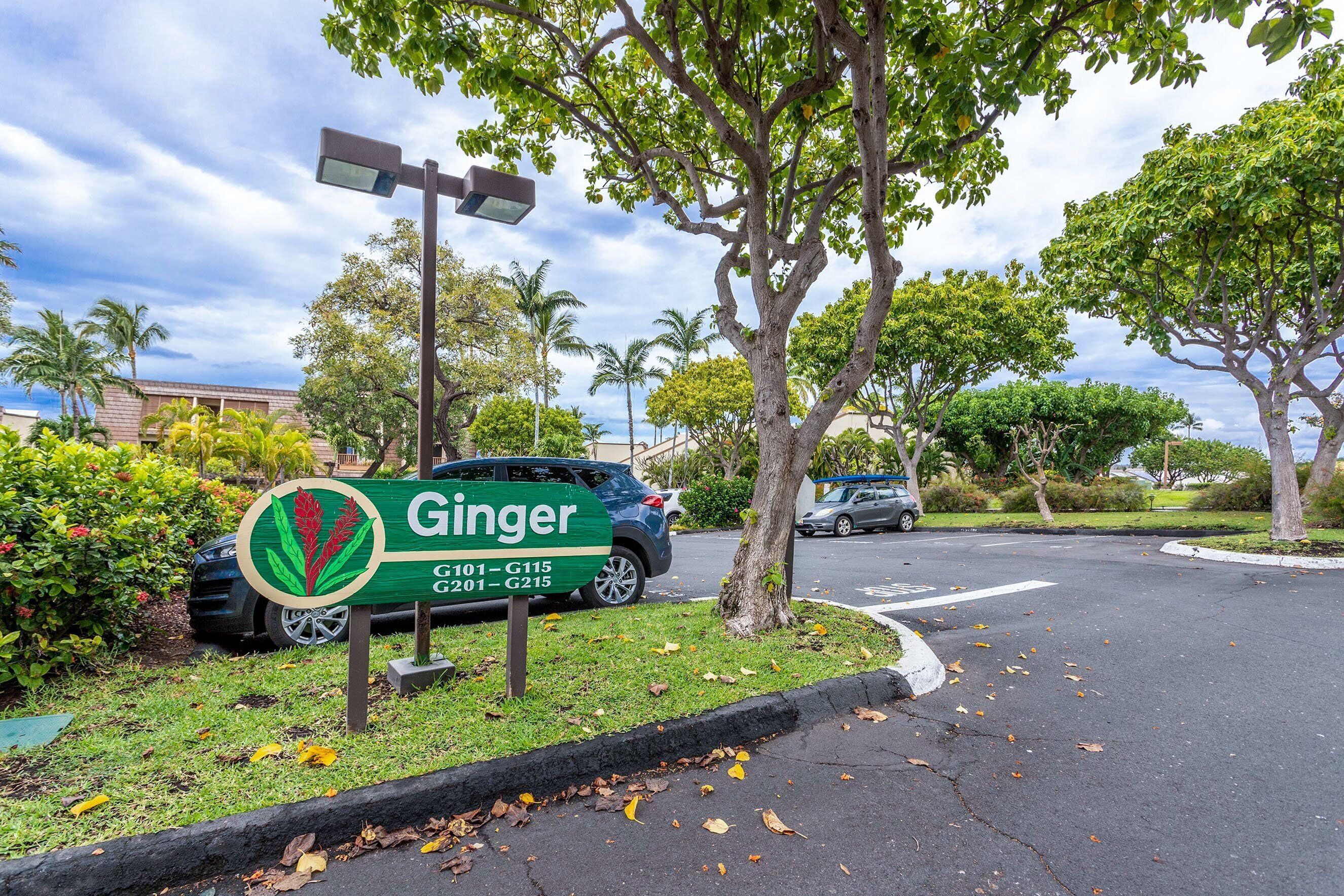 A parking lot with a sign for Ginger, including a green logo and address range G101-G115.