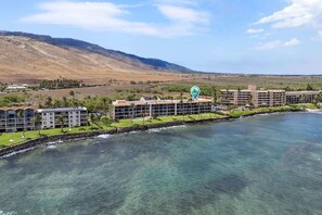 A coastal hotel with multiple buildings, a clear view of the ocean, and a mountainous backdrop. - Lauloa 410 - Top Floor, Oceanfront Lanai, Molokini & Halaeakala Views, Split A/C (Wailuku)
