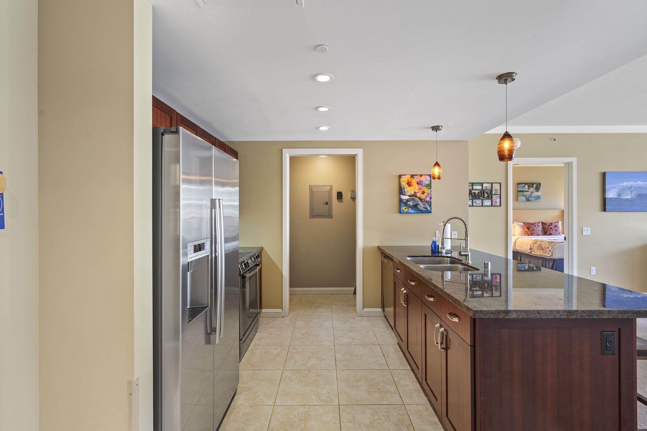 A modern kitchen with a stainless steel refrigerator, a built-in oven, and a wooden island with a sink.