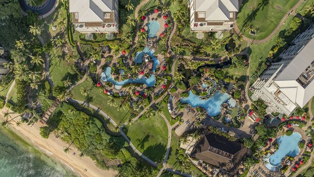 An aerial view of a resort with multiple swimming pools, palm trees, and beachfront access. - Honua Kai Resort Konea 505 Ocean & Sunset View 2BR at Kaanapali (Lahaina)