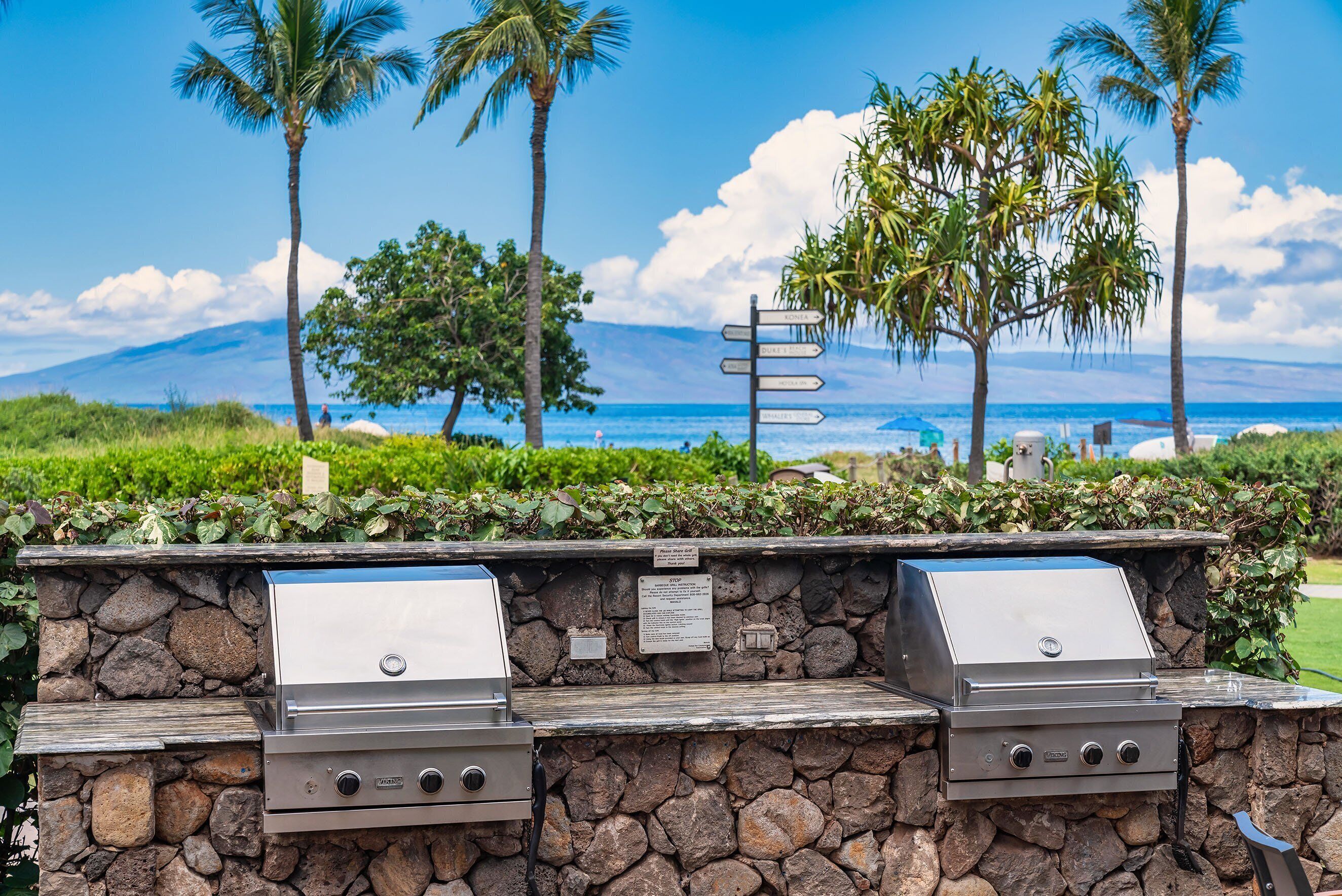 An outdoor grill area with stone walls and a view of the ocean.