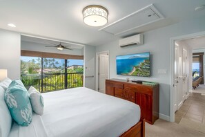 A bedroom with a large bed, a ceiling fan, a TV, and a balcony with a view of palm trees. - Discover Wailea Ekahi 39E - Breathtaking Ocean Views, Renovated, Wi-fi, Split AC (Kihei)