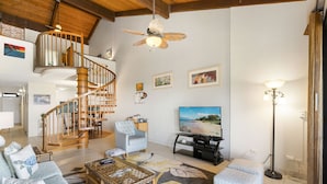 Un salon spacieux avec un escalier en bois, un grand téléviseur à écran plat et un coin salon confortable.