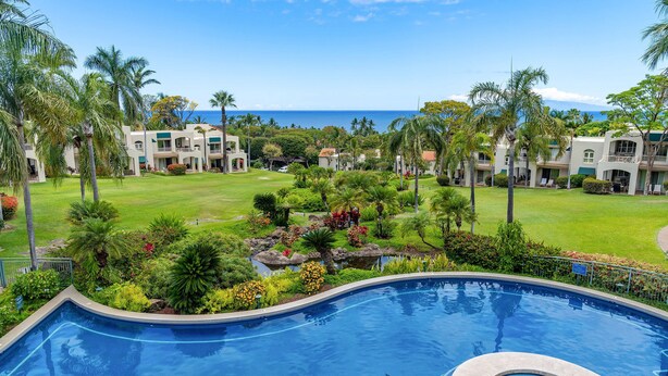 Un resort con piscina, abundante vegetación y vista al océano.